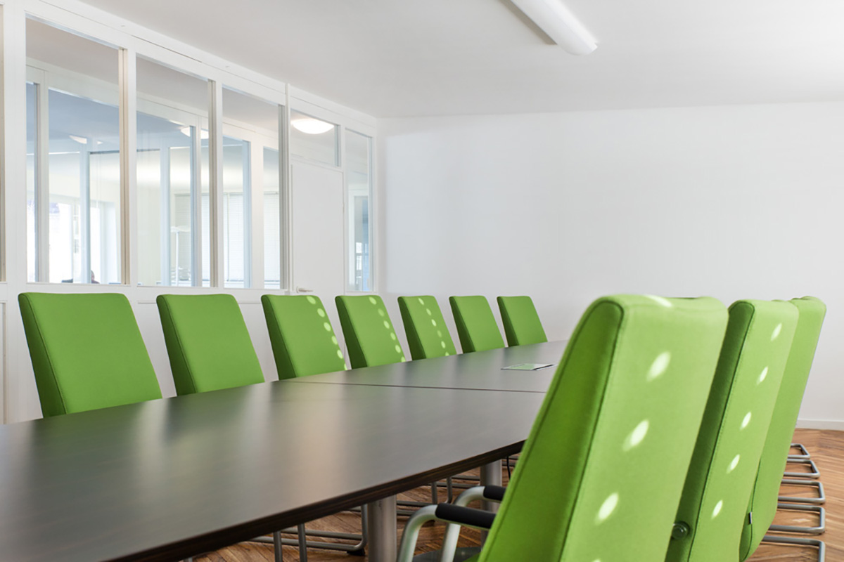 Konferenztisch mit grünen Stühlen